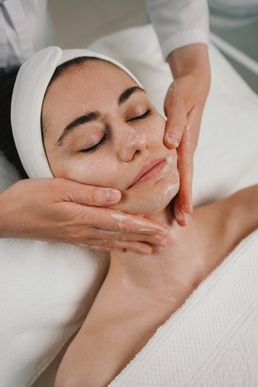 Beautician's hands applying foam cleanser for massaging client's face. Healthy skin care, exfoliation scrub soap with cleansing product. Skincare spa relax concept.